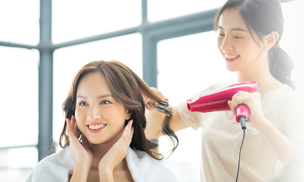 ドライヤーで髪を乾かしている美容師と女性